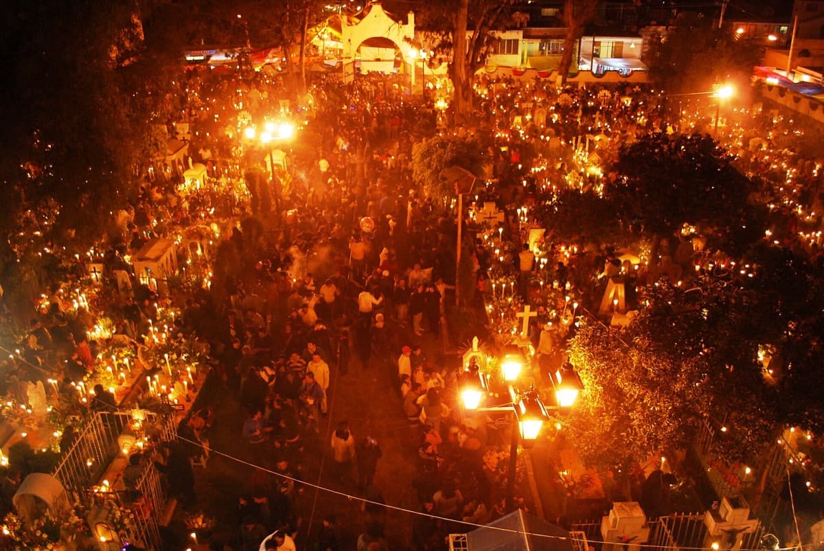 A cemetery covered with candles and marigolds seen from above at dusk