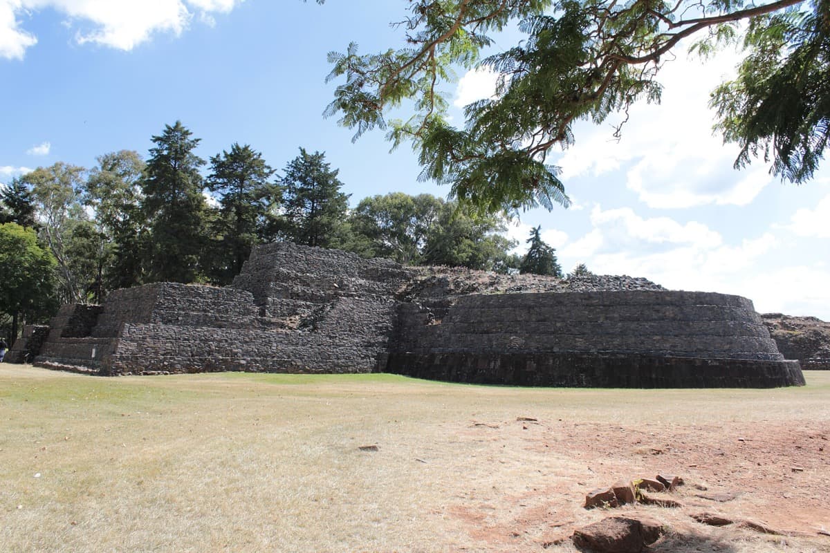 Rounded stone pyramids on a grassy platform above a lake