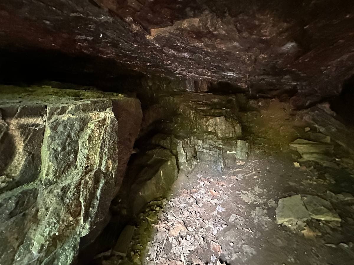 A low rock ceiling over a floor of loose stone inside a shallow cave