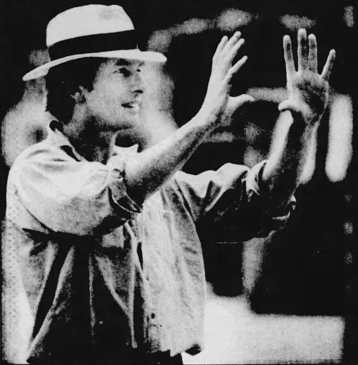 Peter Weir in a straw hat, hands raised, directing