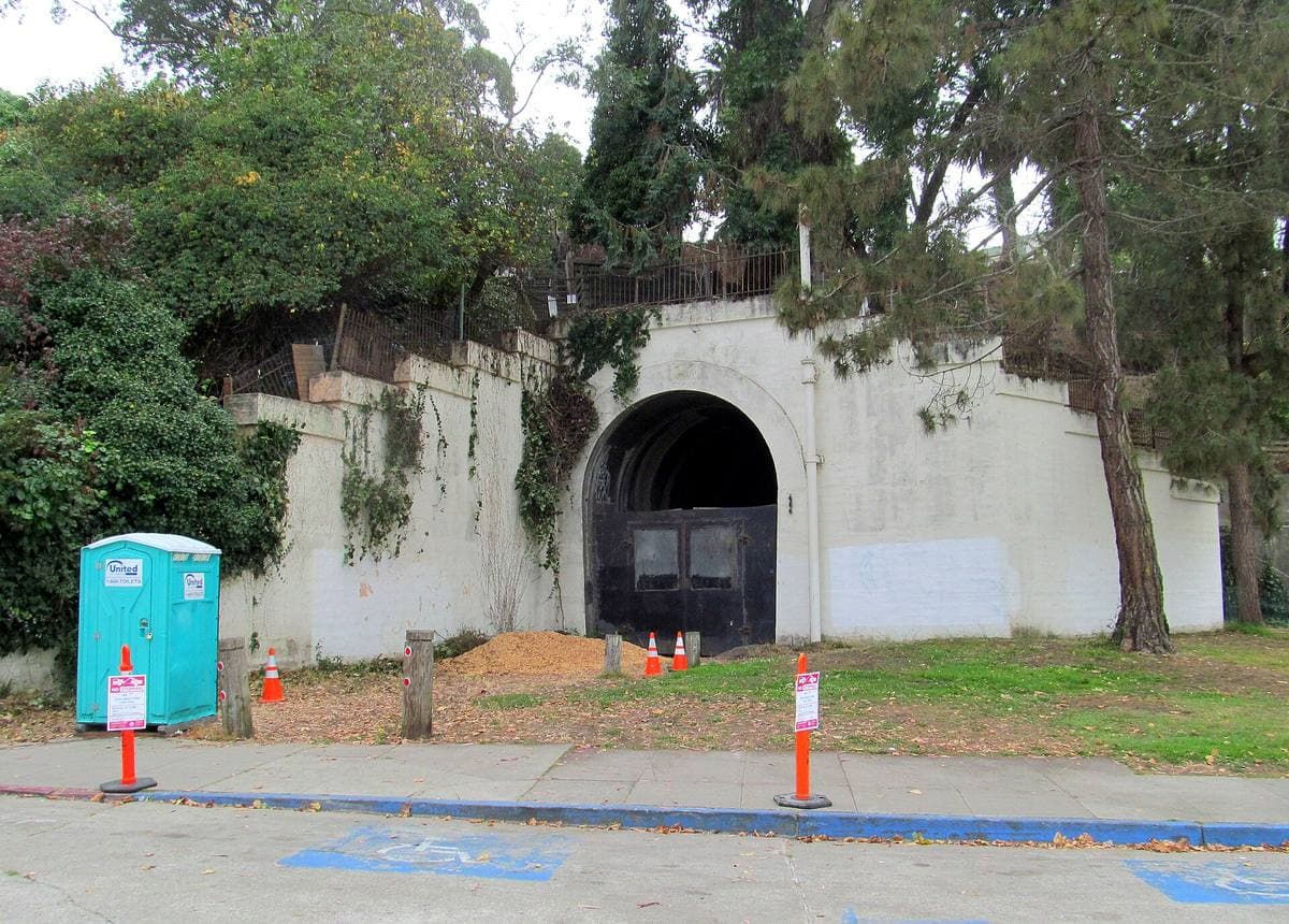 A sealed concrete railway tunnel mouth in a grassy slope