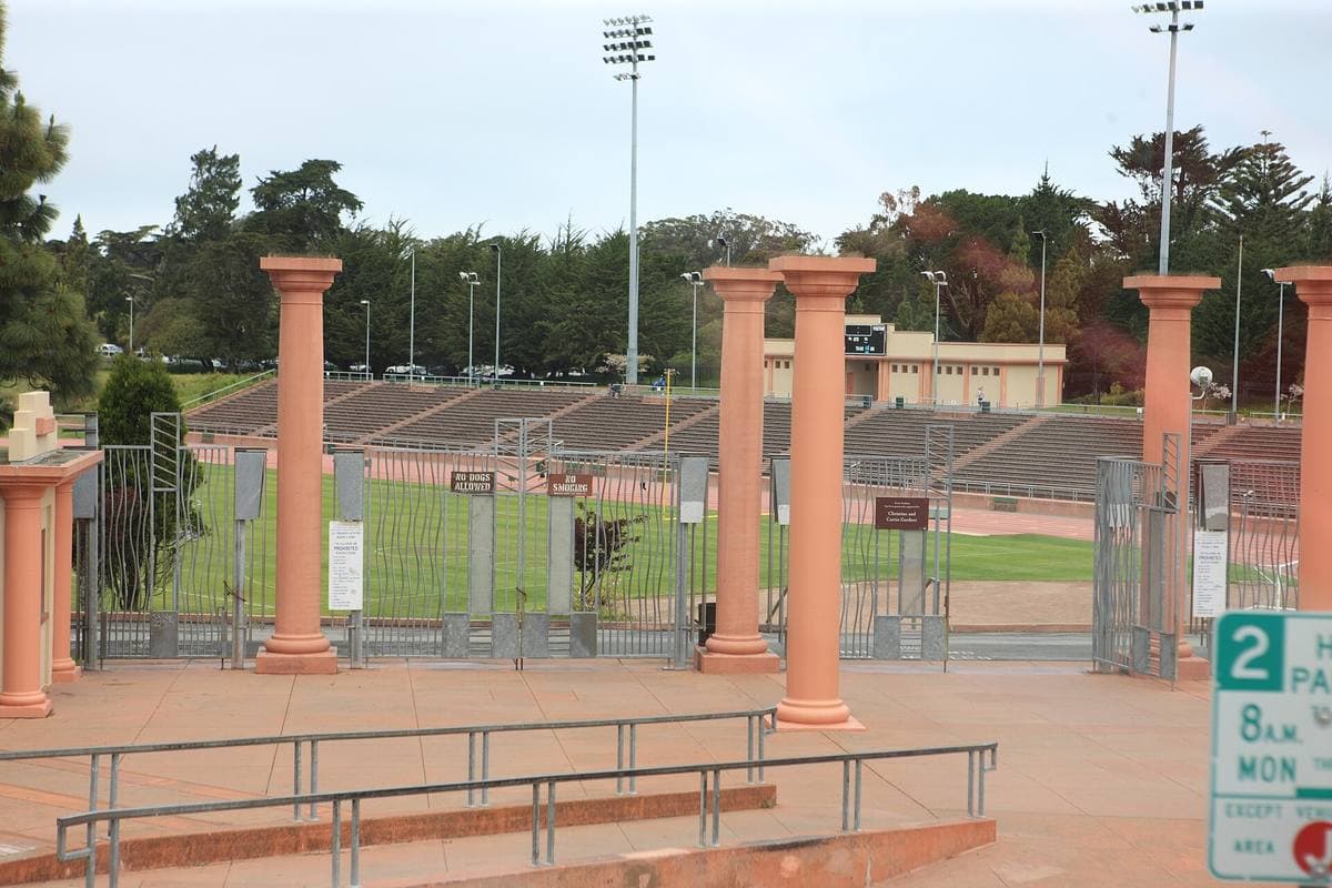 Pink classical columns in front of a running track and low stands