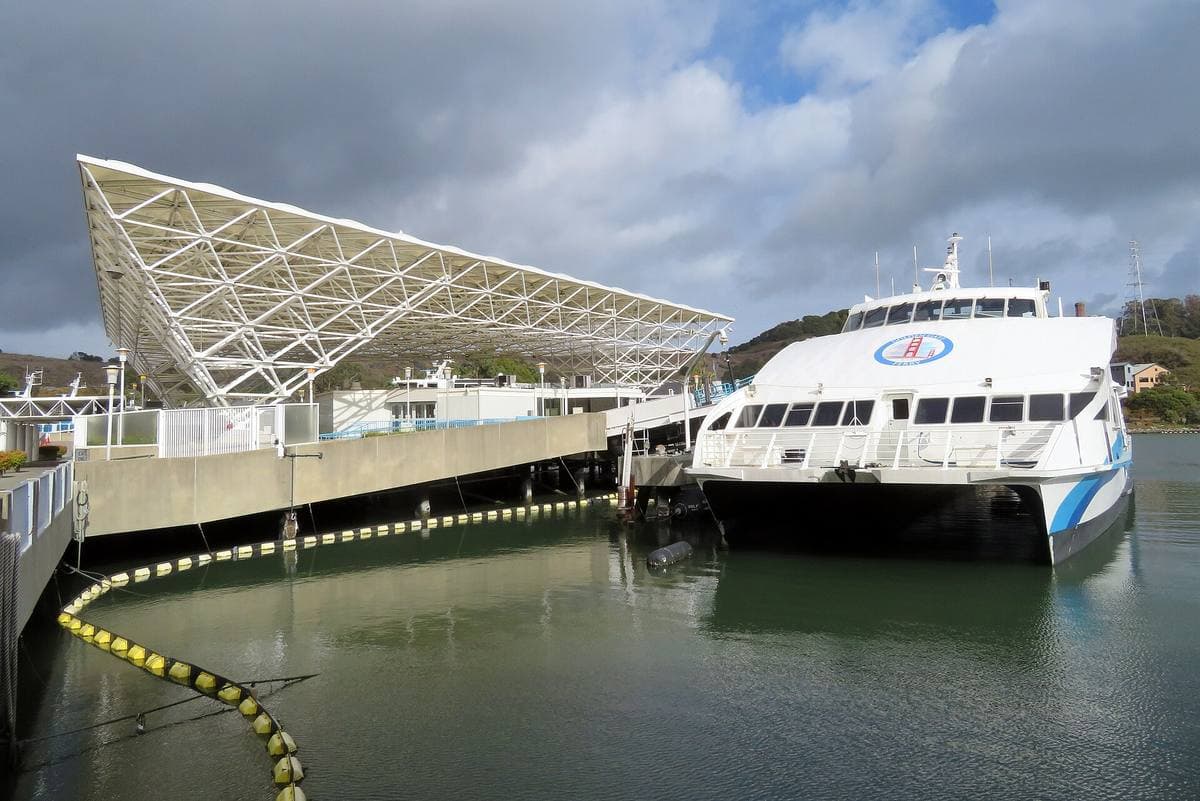 A white ferry moored beside a terminal under a white space-frame canopy