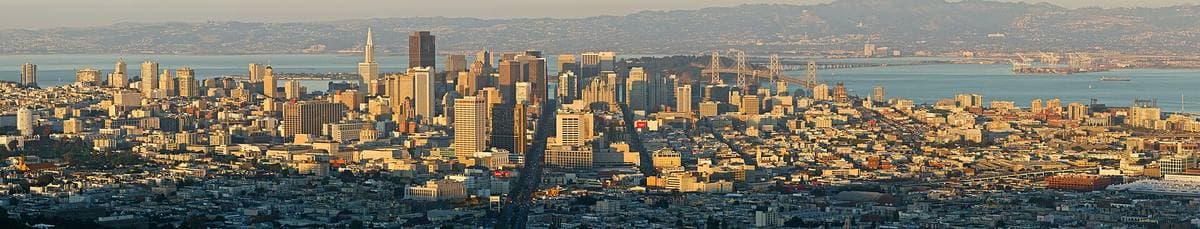 A wide view across San Francisco at dusk, the downtown towers and the bay beyond