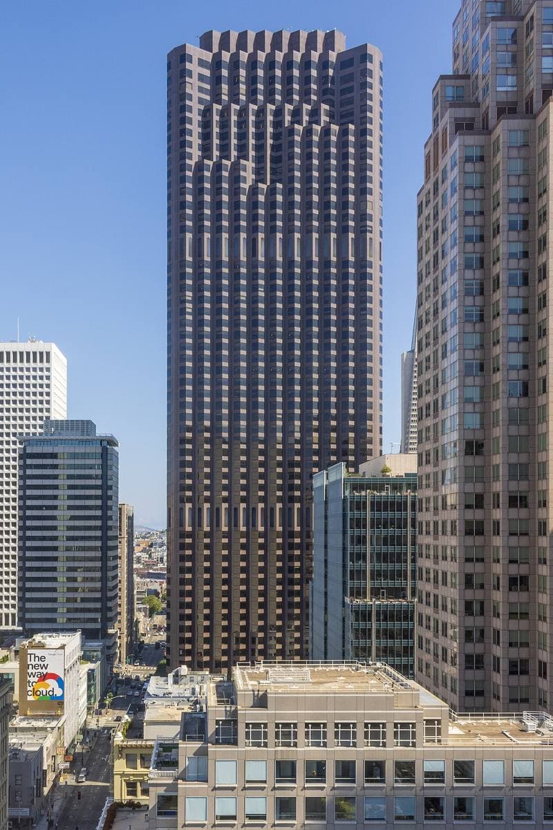 A dark granite tower with bay-window ribs rising above the Financial District