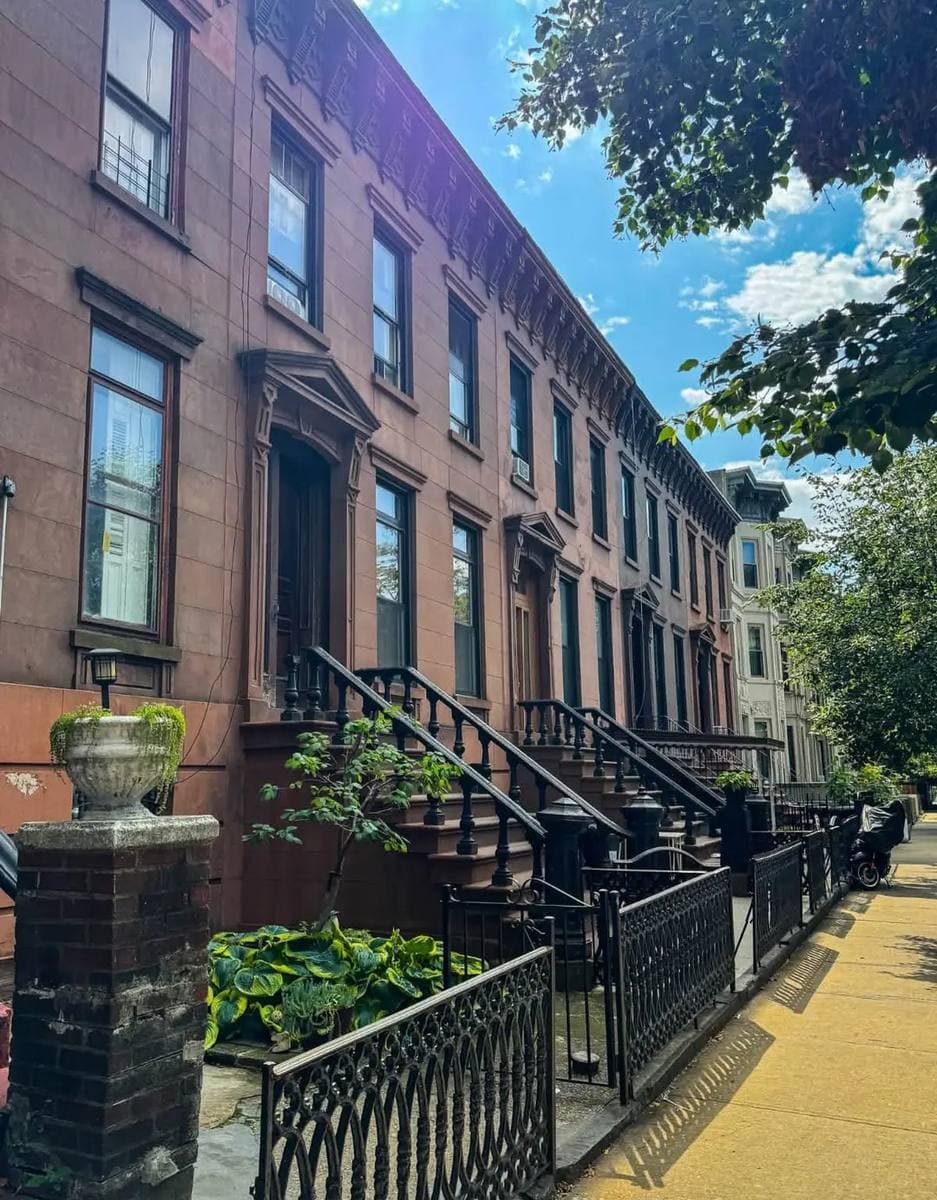 A long brownstone terrace with stoops in summer light