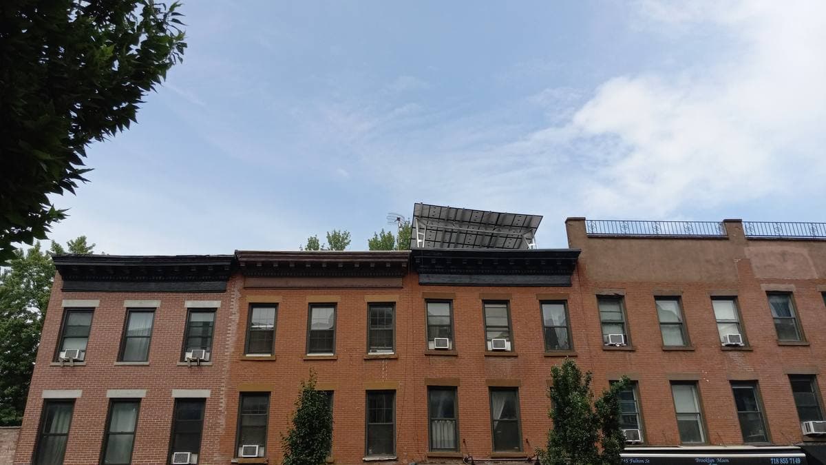 A terrace of brick houses against a summer sky in Fort Greene