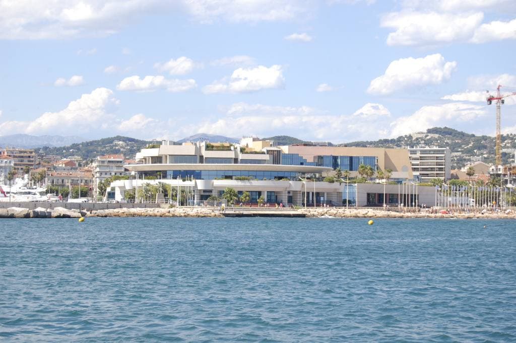 The low white Palais des Festivals on the Cannes seafront, seen across blue water