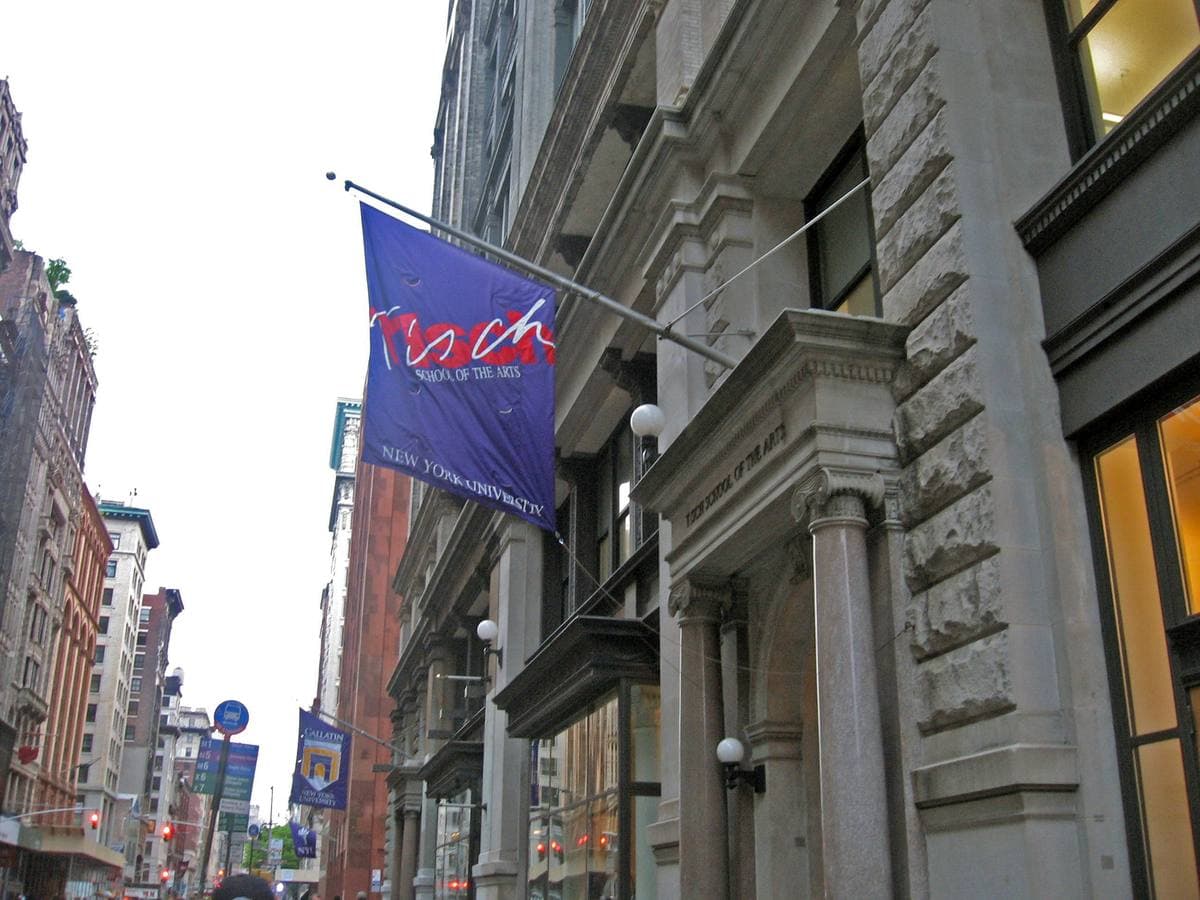 A stone building on Broadway hung with purple Tisch School of the Arts banners
