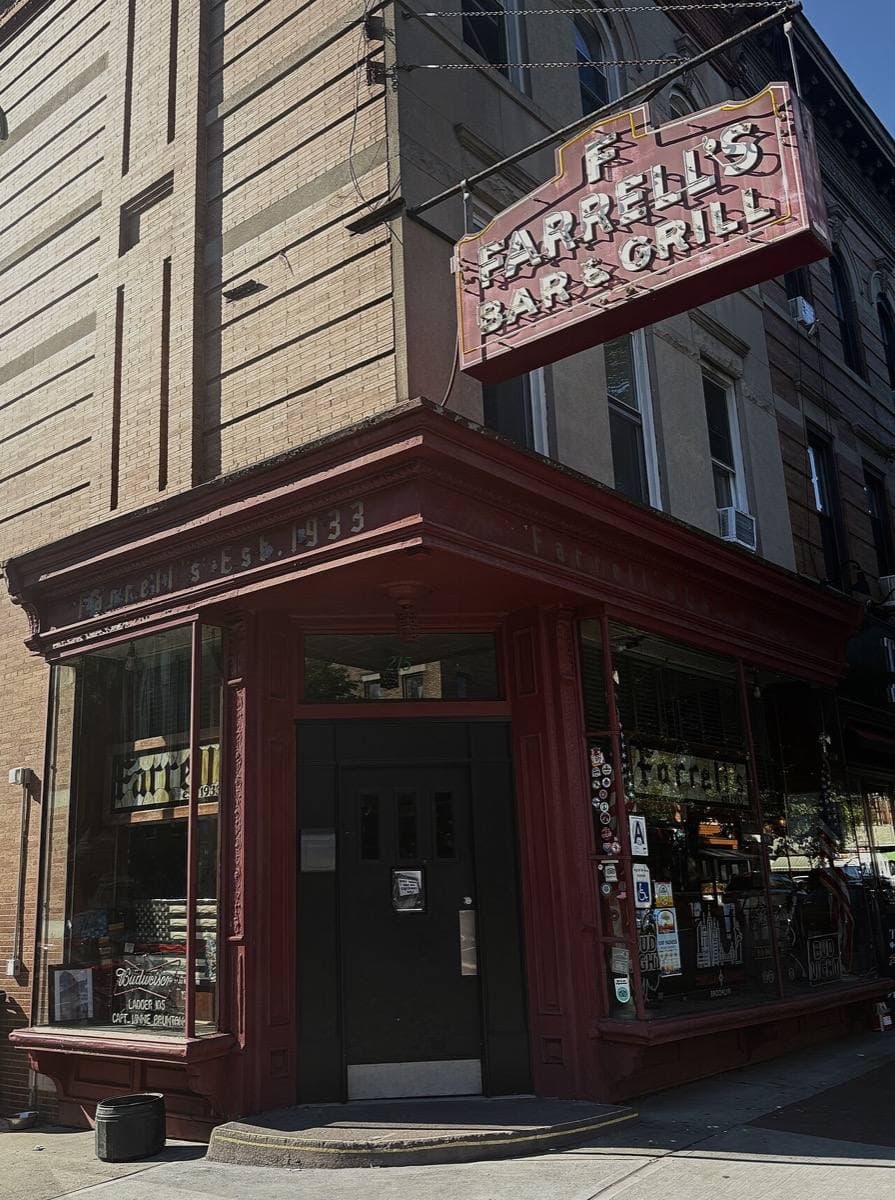 A corner bar with a red frontage and a projecting sign reading Farrell’s Bar and Grill