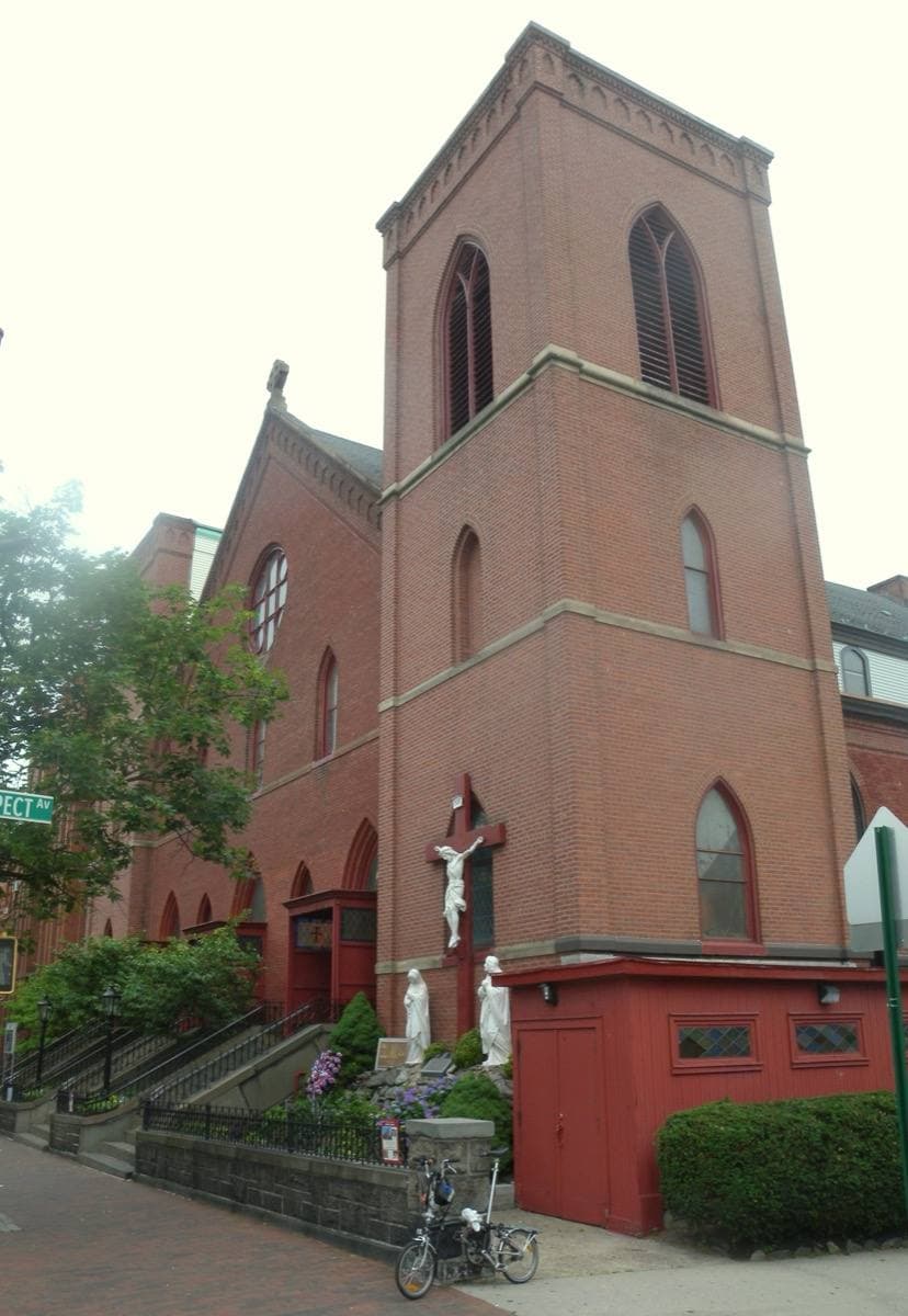 A red-brick church with a square tower and a pointed window