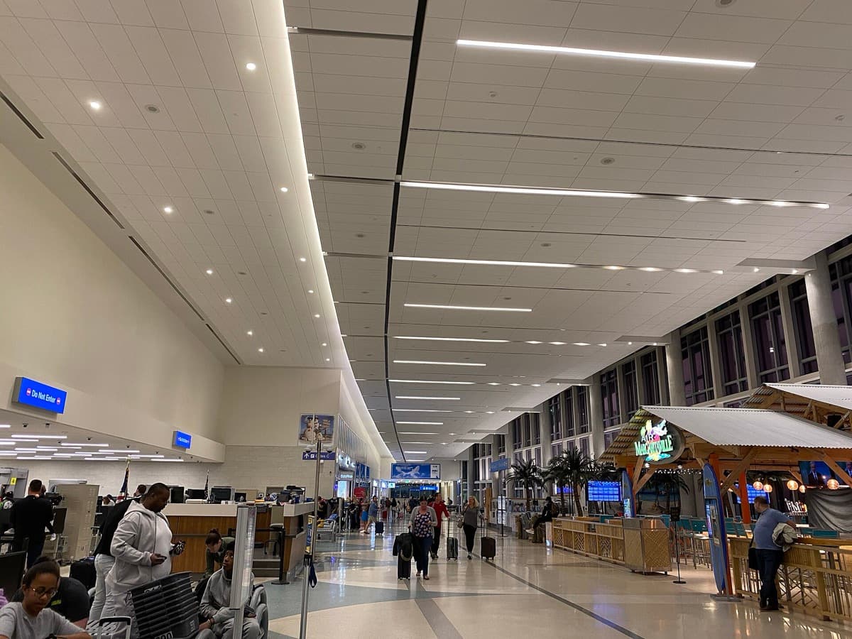 A long bright airport terminal hallway with gates on one side