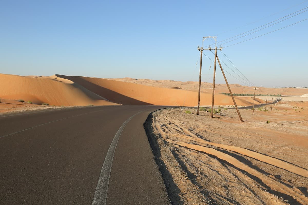 A sharp orange sand ridge with wind-rippled slopes under a clear sky