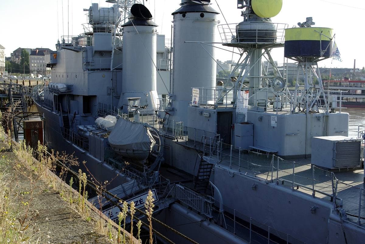 A grey destroyer moored along a city quay on the Loire