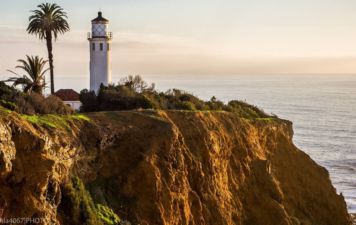 A white lighthouse on a cliff above the Pacific