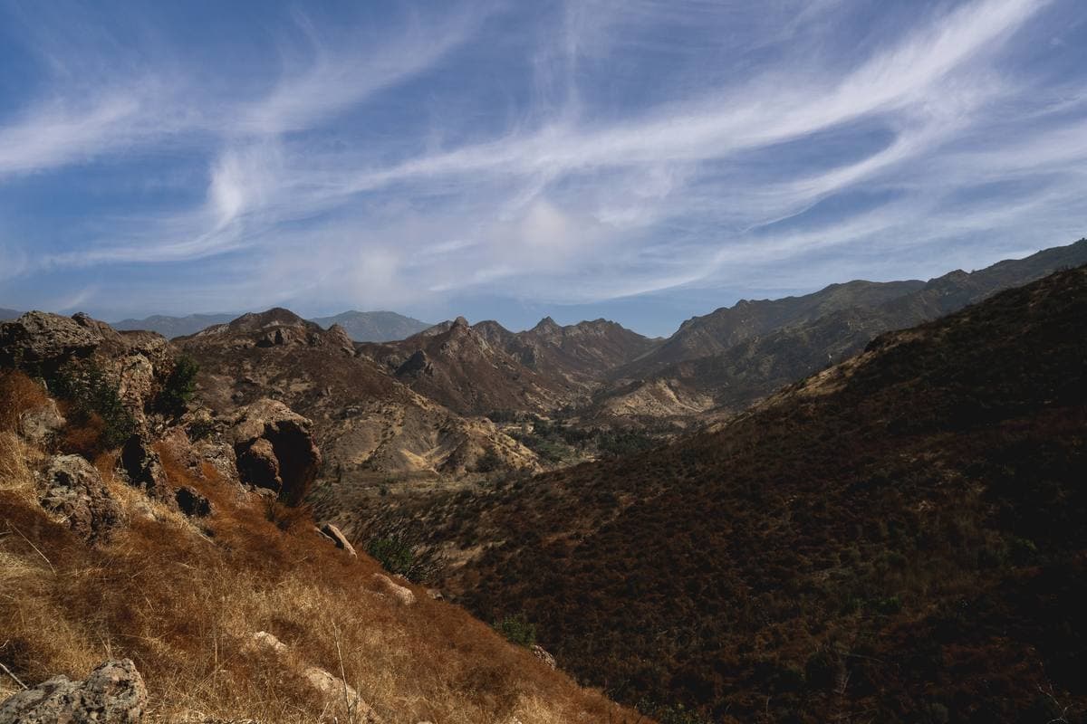 Dry rocky ridges folding away under streaked white cloud