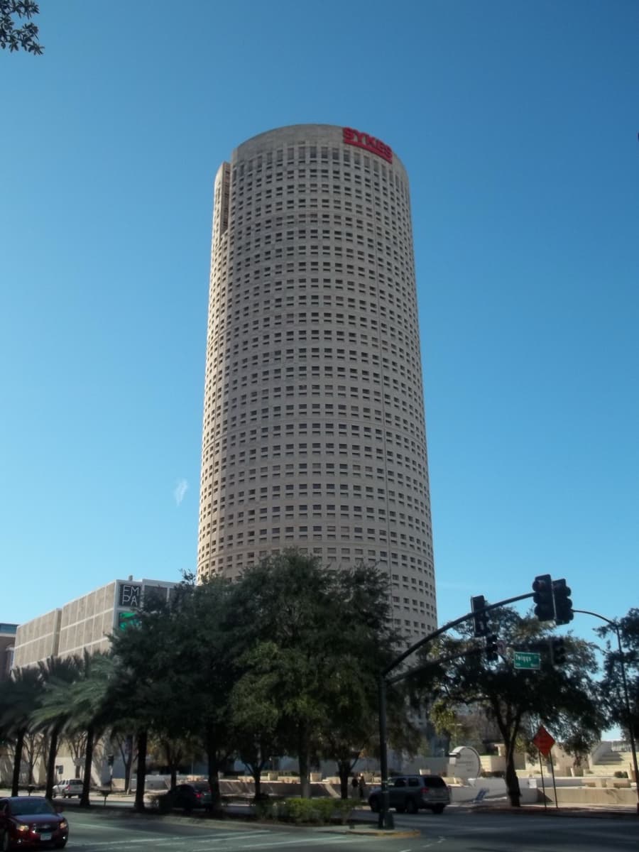 A tall cylindrical office tower with a crown of slanting cuts rising above Tampa.