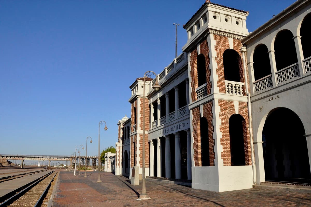 A long Spanish Revival railway hotel building with arches and a tower