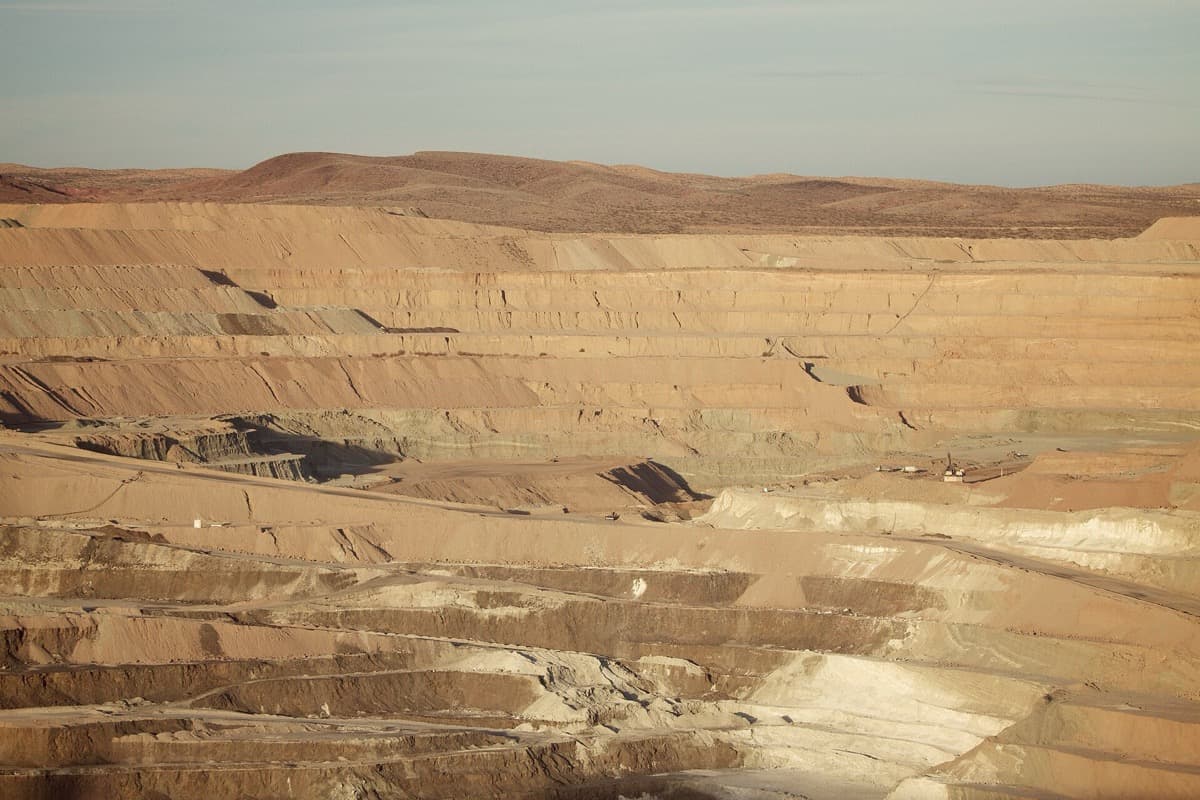 A vast open-pit mine with pale terraced walls in the desert