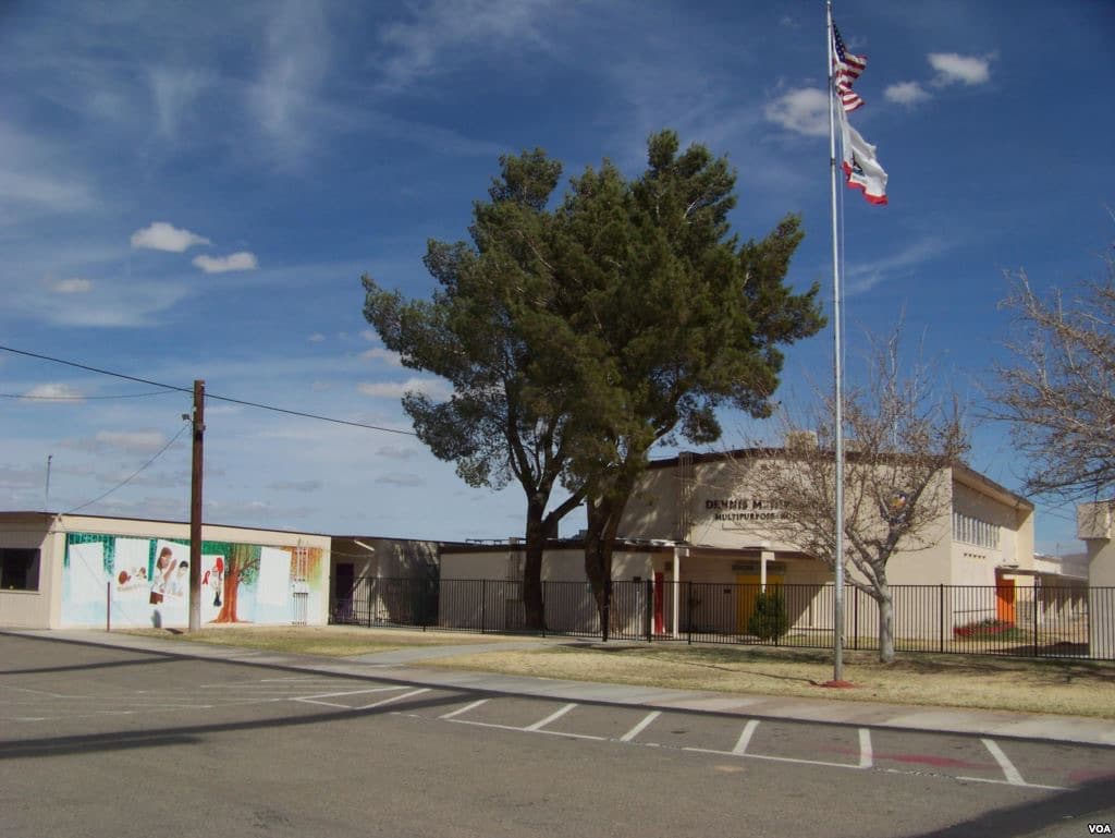 A low school building and playground in a dry desert town