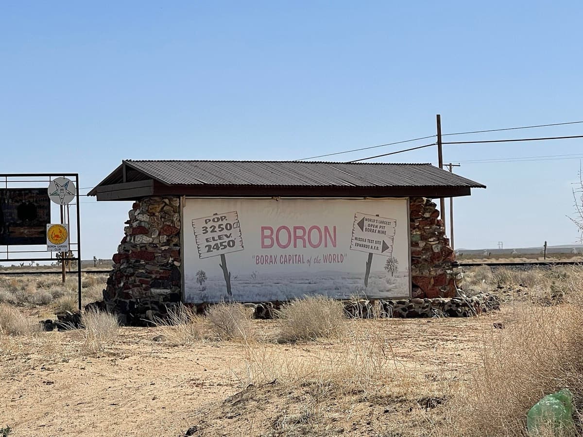 A roadside welcome sign for the desert town of Boron under a wide sky
