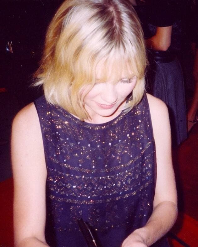Kirsten Dunst with short blonde hair, looking down, smiling
