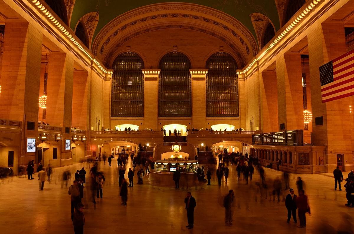 A vast arched hall lit gold, crowds crossing the floor