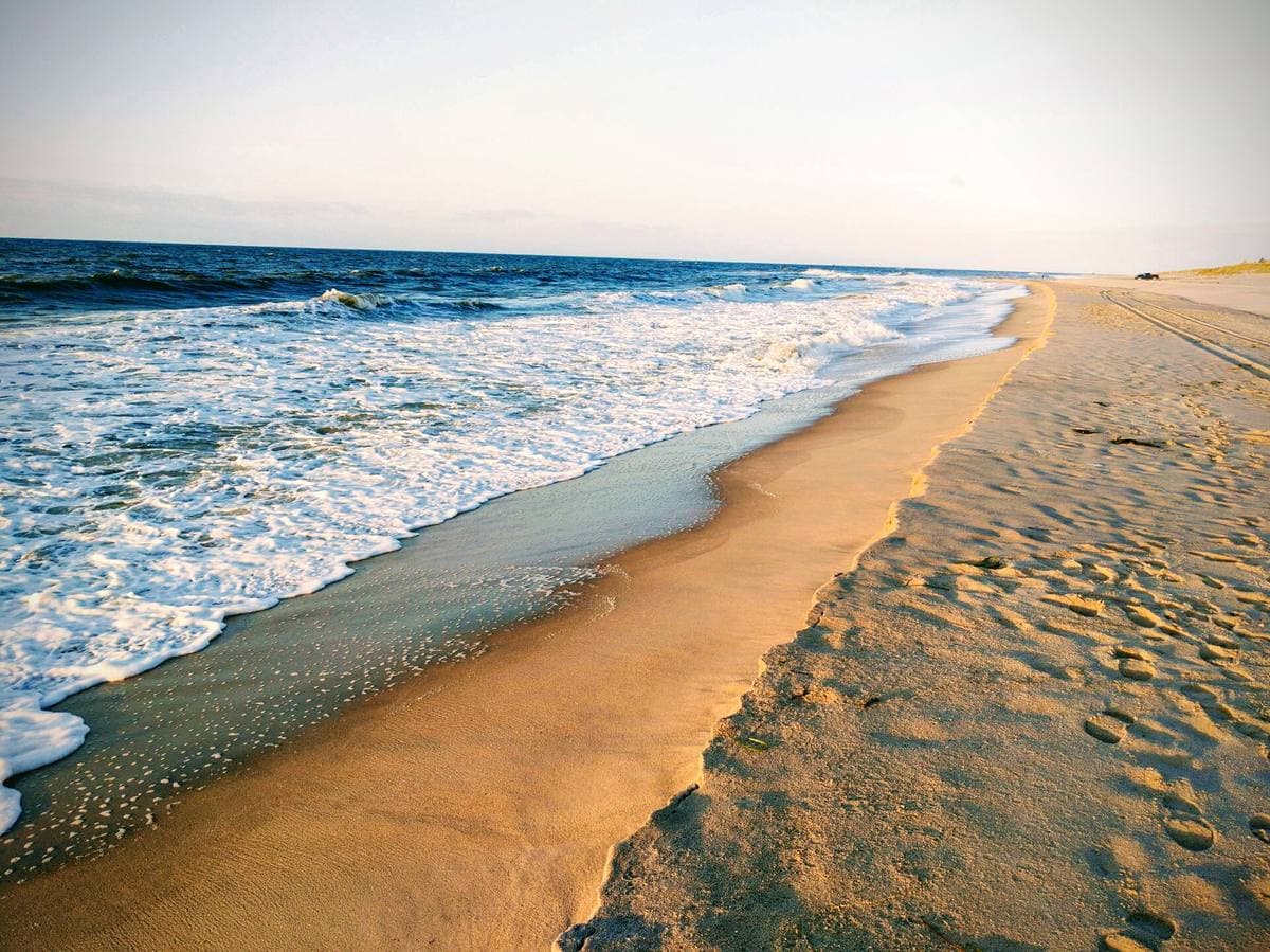 Waves running up a wide sandy beach at sunrise