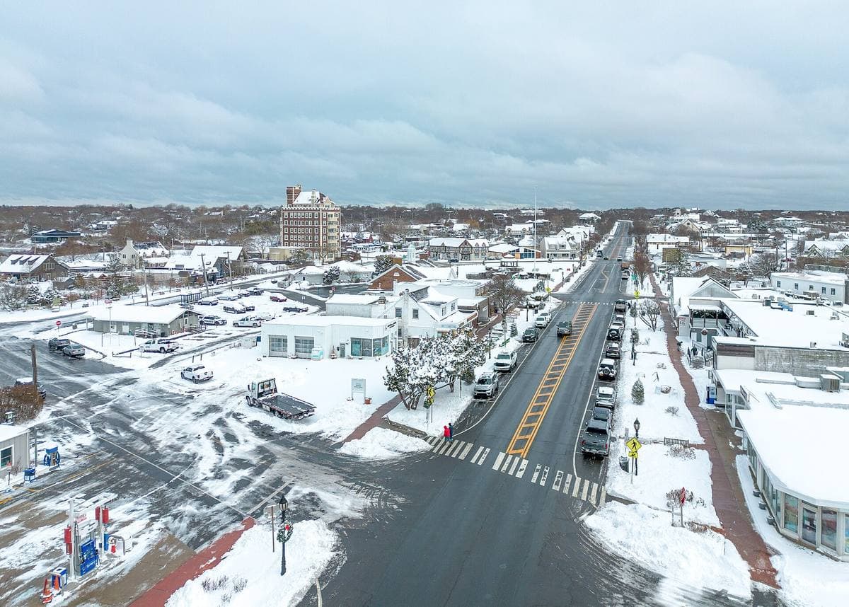 Aerial view of a small town covered in snow, a wide road running to the sea