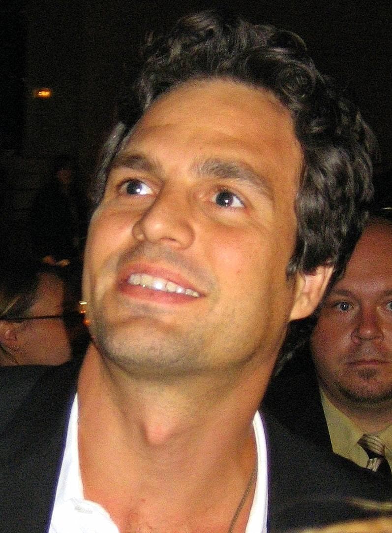 Mark Ruffalo smiling and looking up, in a dark jacket