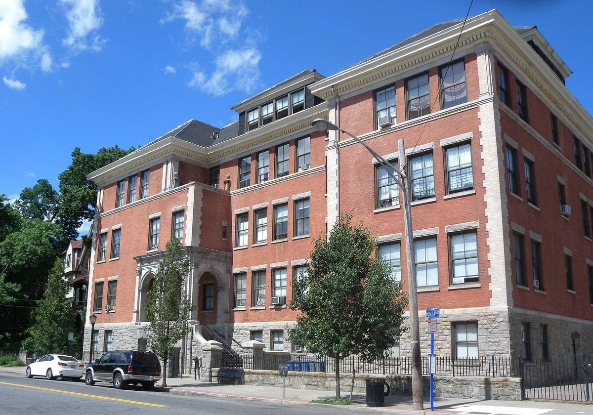 A red-brick former school on a sunny street corner