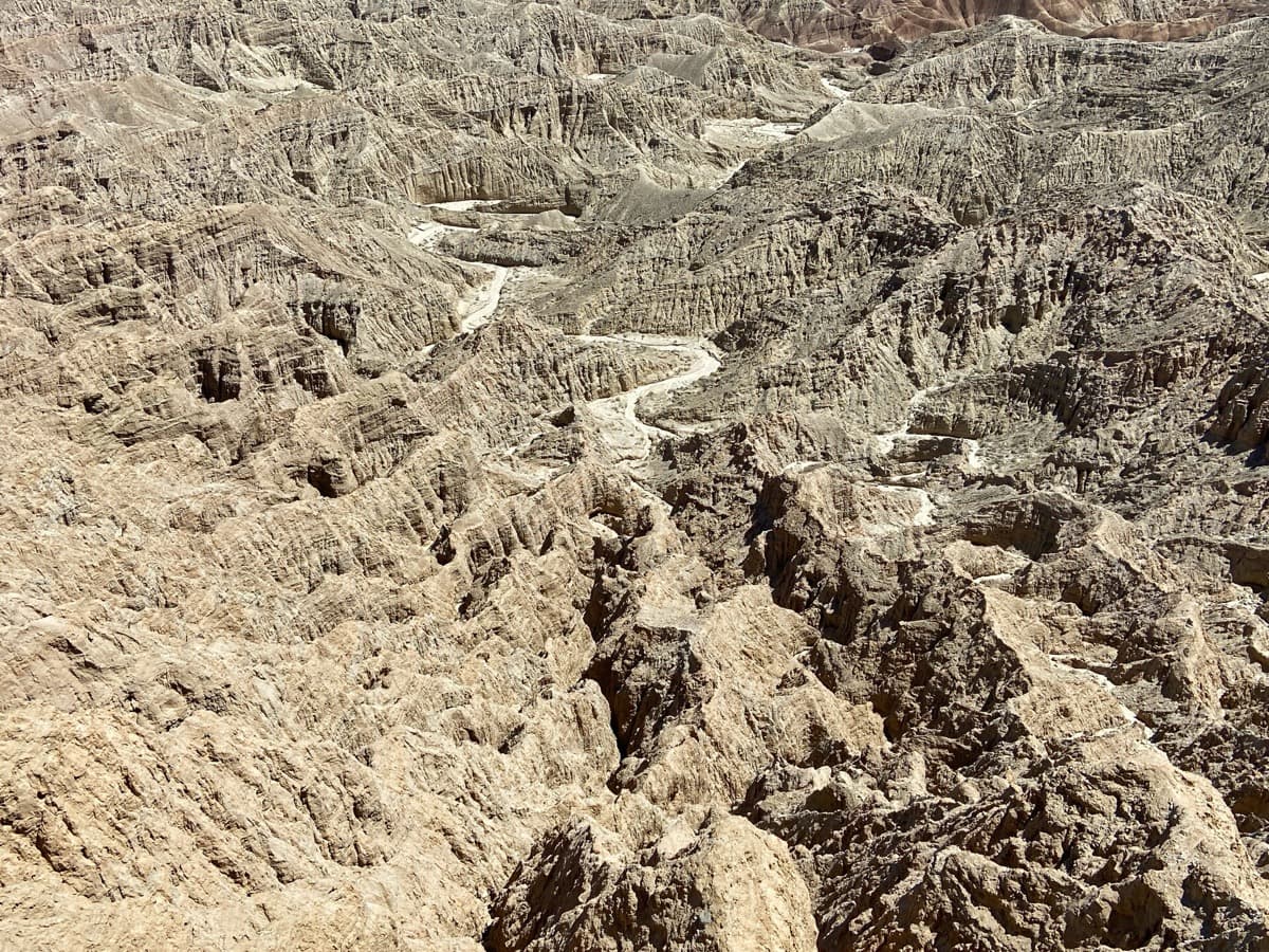 Eroded badlands of pale ridges and gullies under a wide sky