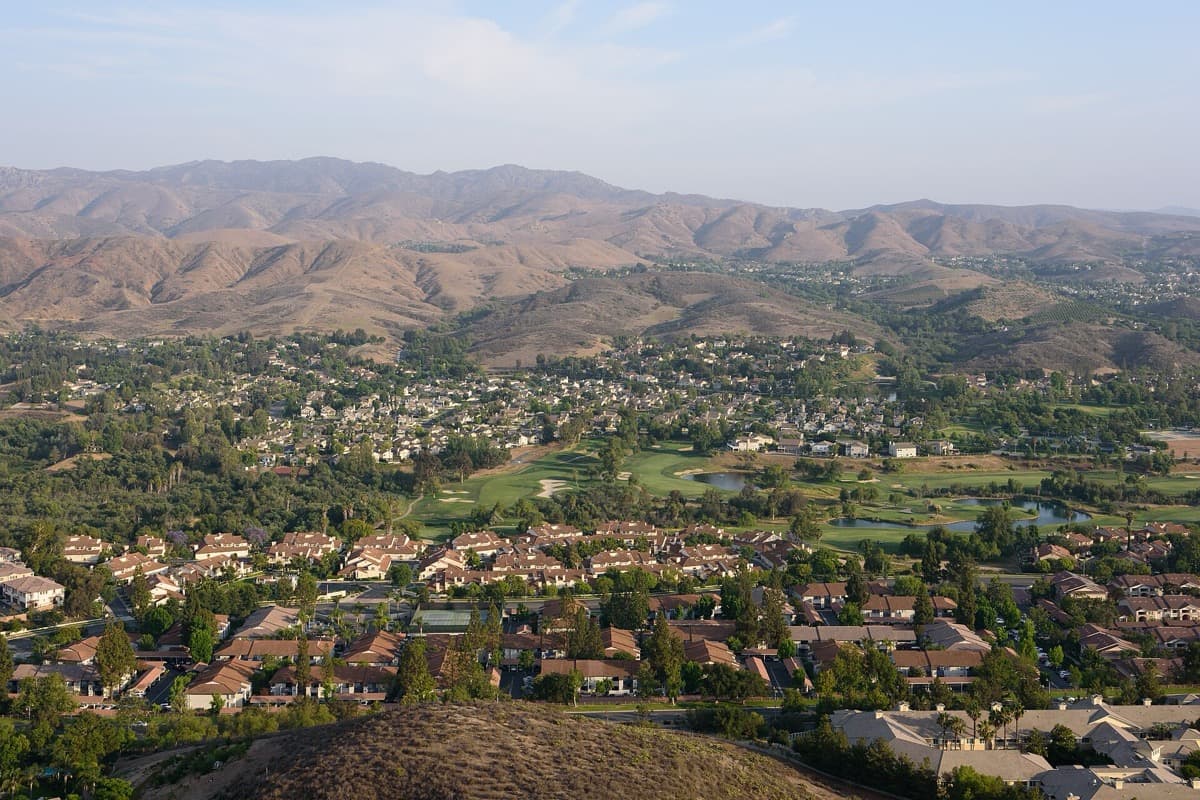 Suburban rooftops below dry golden hills