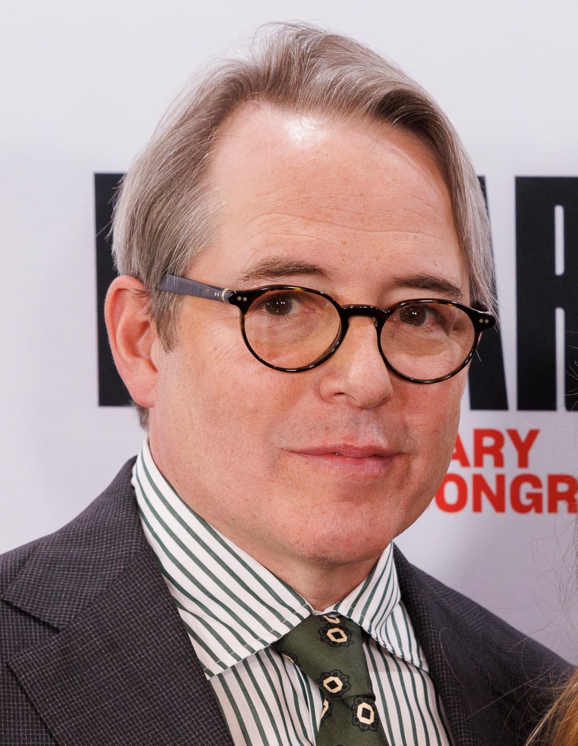 Matthew Broderick in round glasses and a striped shirt and tie