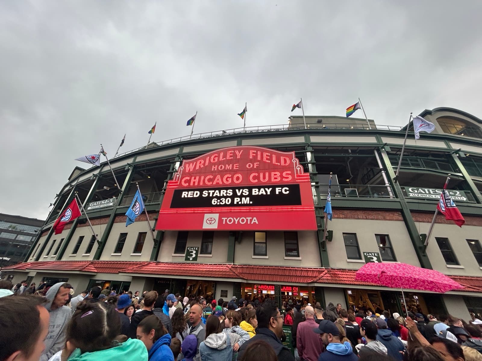 The red Wrigley Field marquee above a crowd at the ballpark entrance