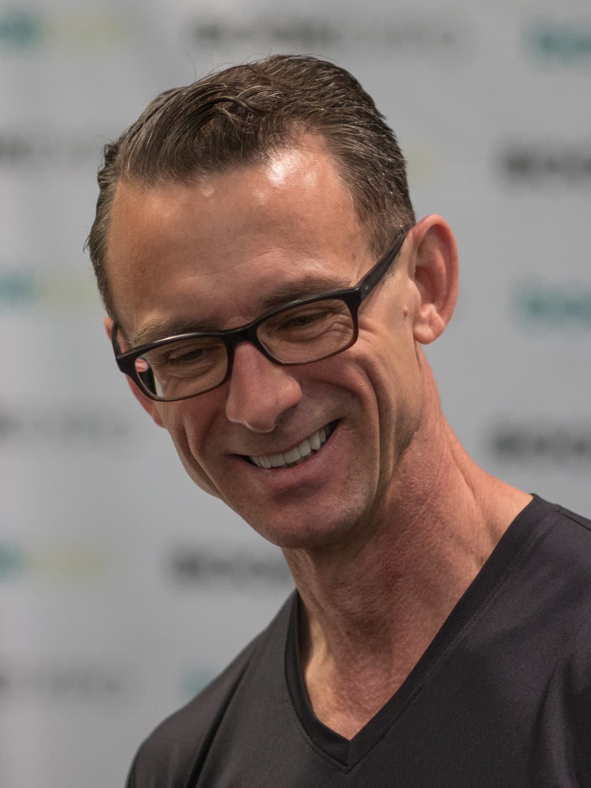 Chuck Palahniuk smiling, in glasses and a black T-shirt