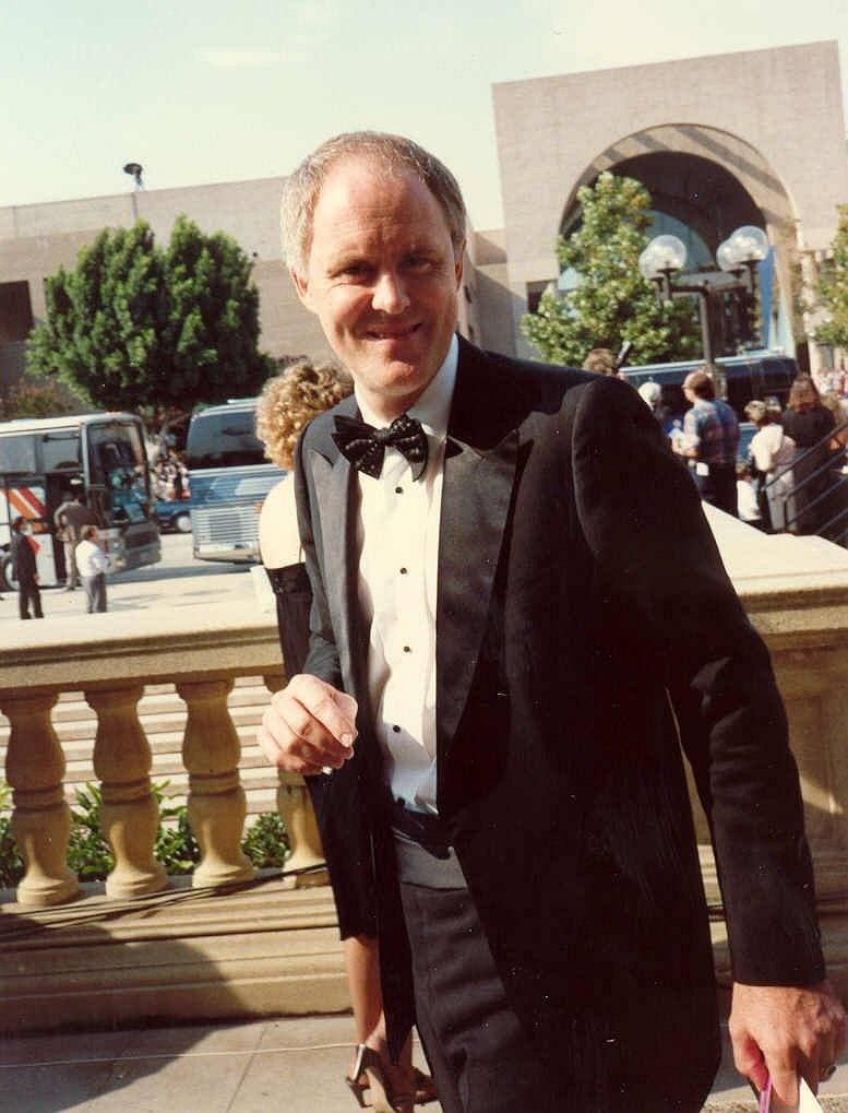 John Lithgow in a dinner jacket and bow tie, smiling, outdoors