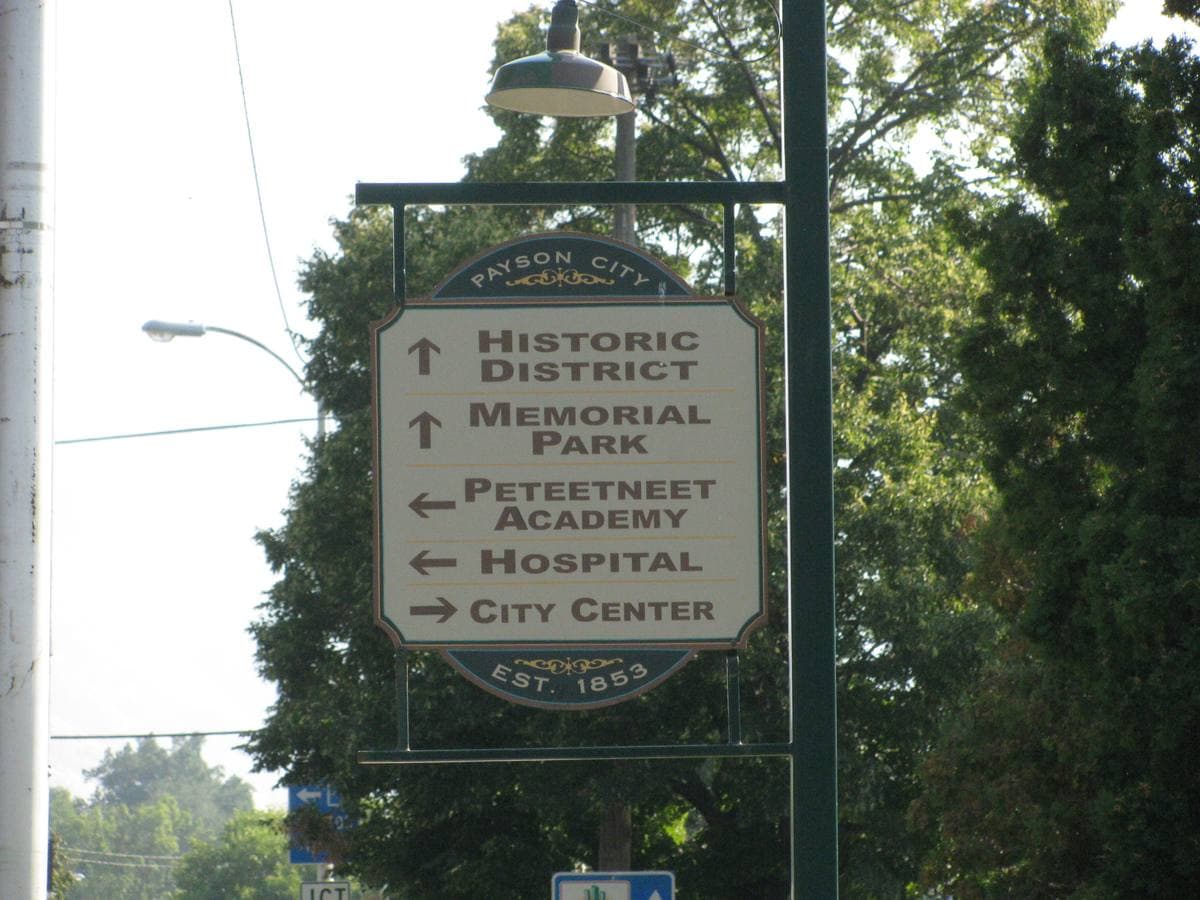 A green street sign with arrows to the Historic District, Memorial Park, Peteetneet Academy and the hospital