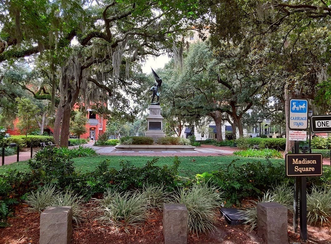 A garden square with a bronze statue among live oaks hung with Spanish moss