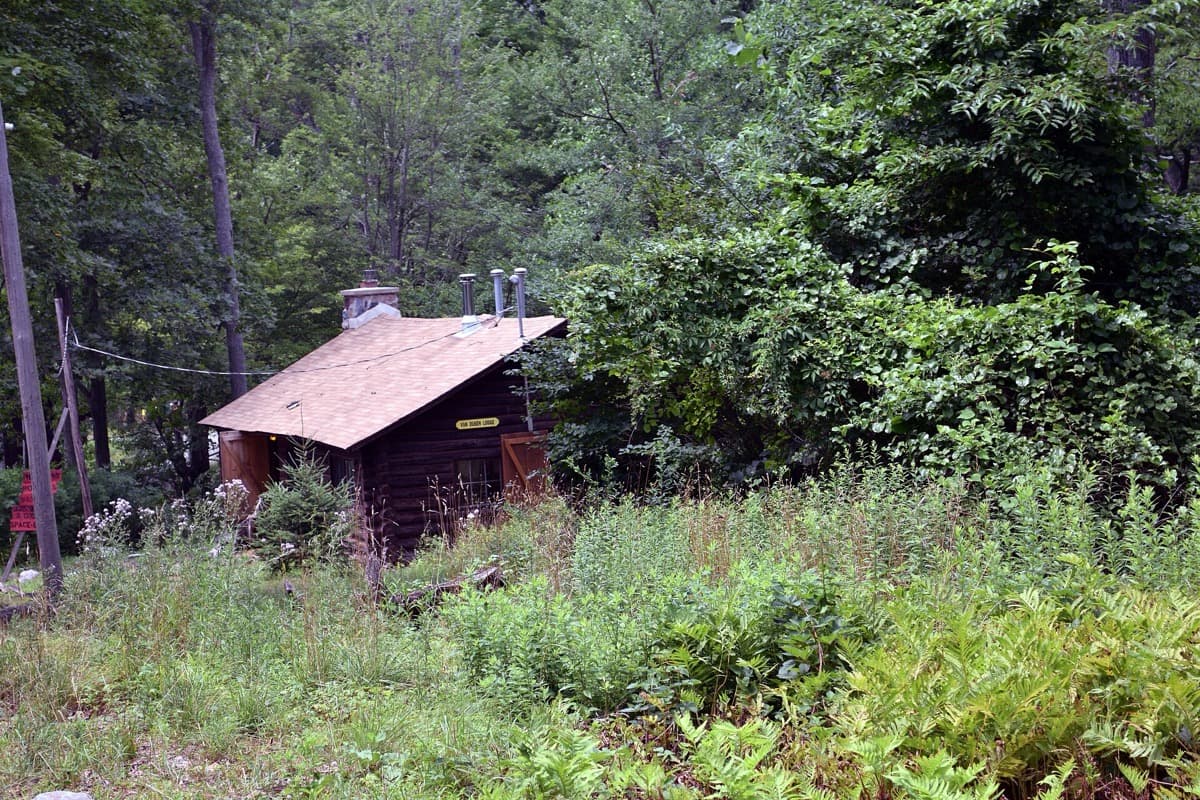 A wooden lodge among trees at a summer camp