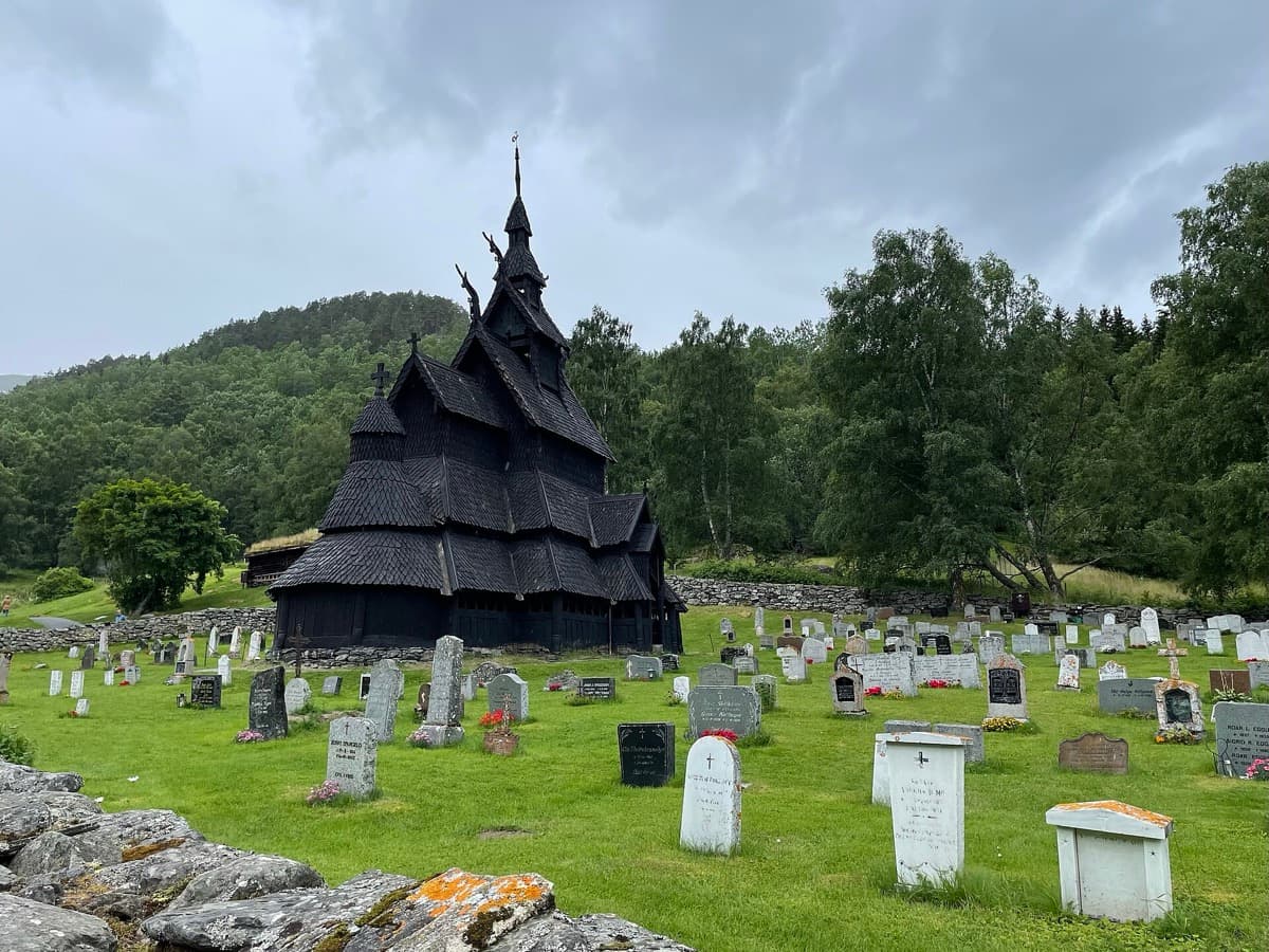 A dark, tiered timber church with shingled roofs stacked one above another