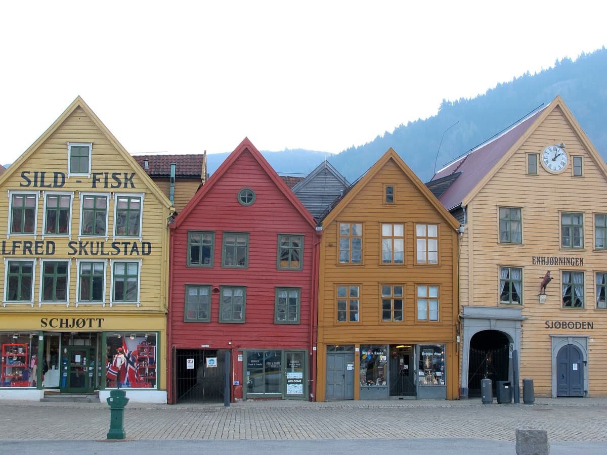 A row of tall, narrow, brightly painted wooden gables along a quay