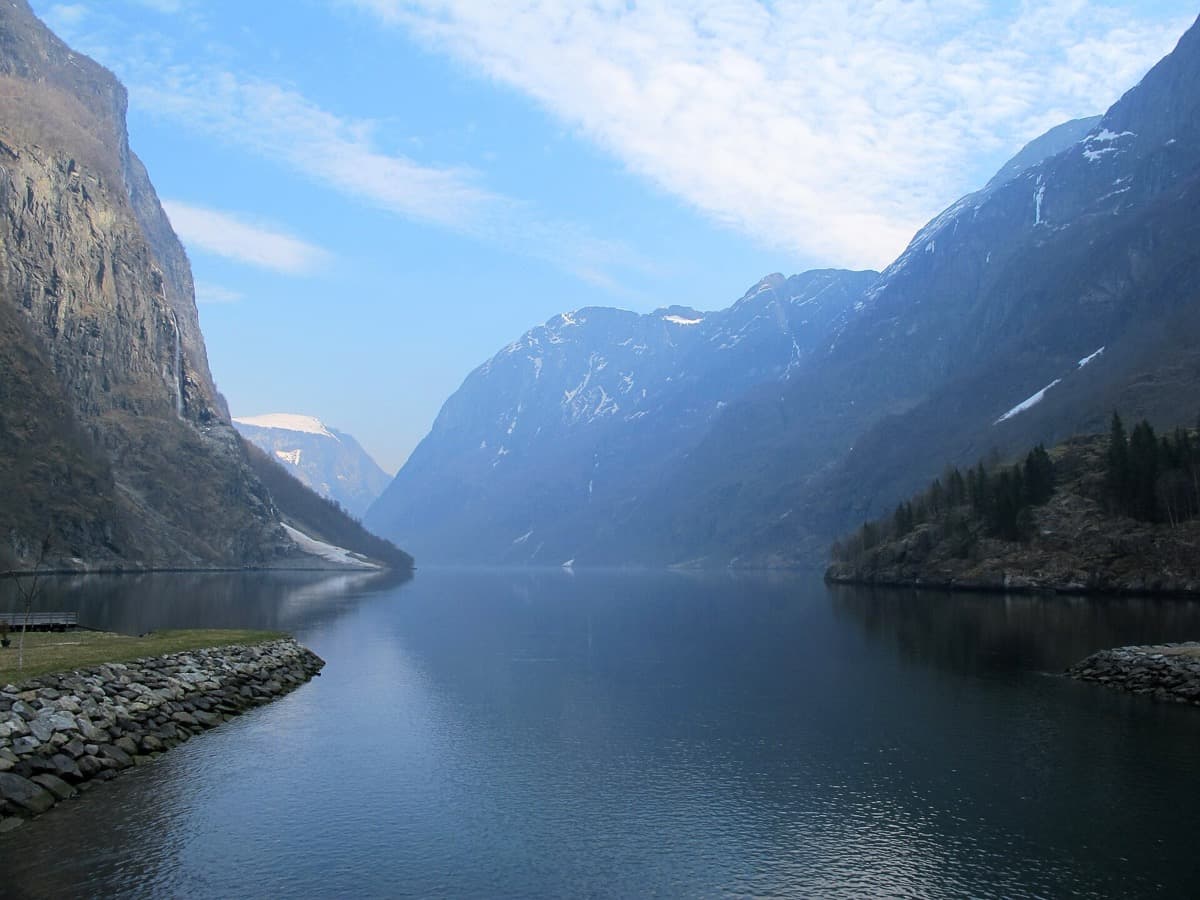 Steep, snow-streaked mountain walls dropping to a narrow stretch of water