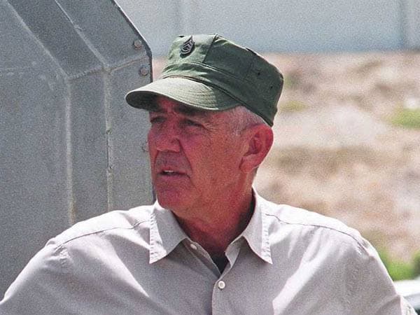 R. Lee Ermey in a green cap and a pale shirt, looking to one side