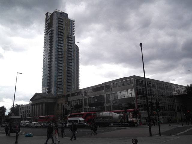A long college building at a busy junction, a tower block behind