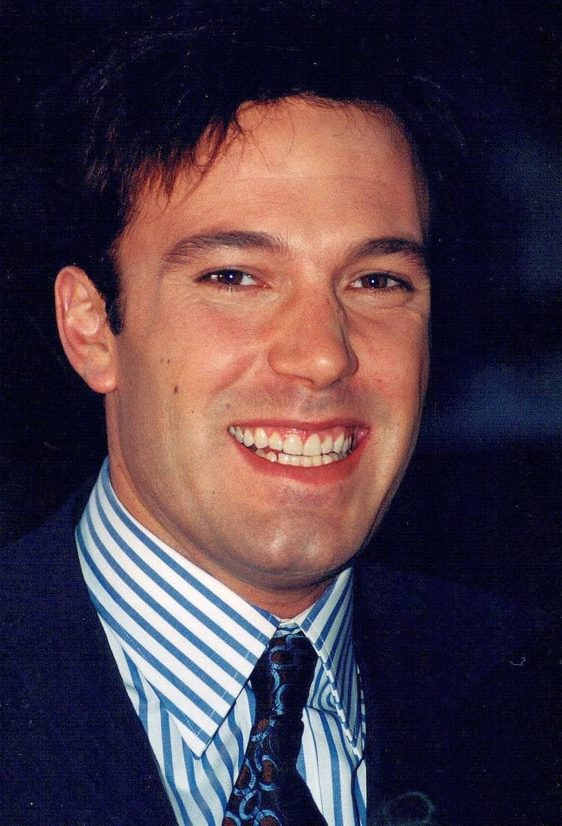 A young Ben Affleck grinning, in a striped shirt, dark tie and jacket