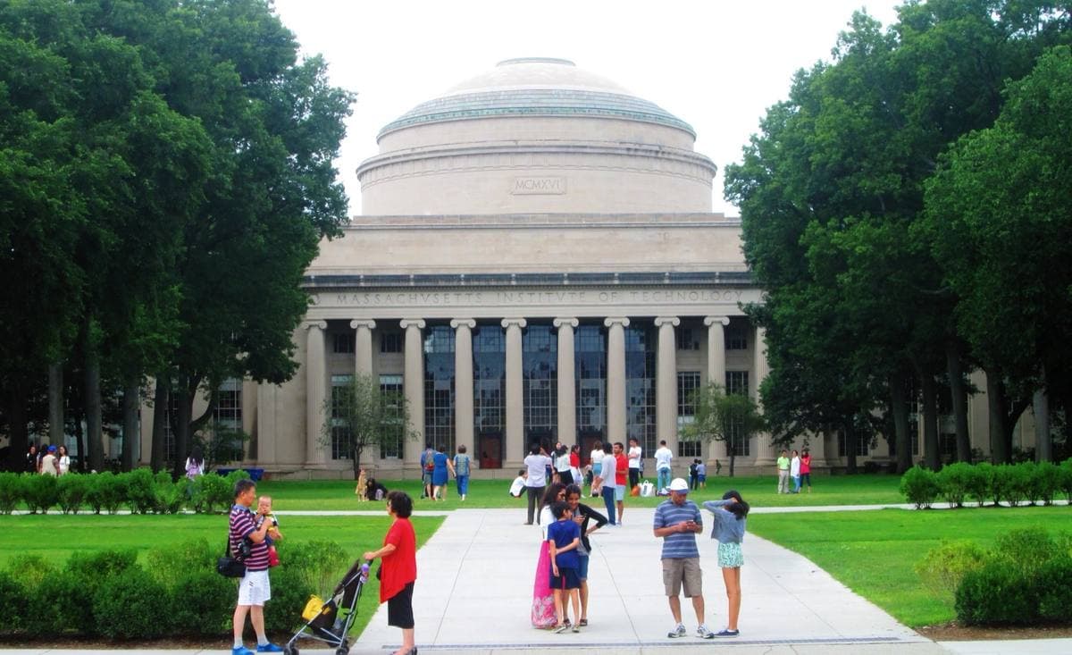 A columned building with a great dome behind a lawn where visitors walk