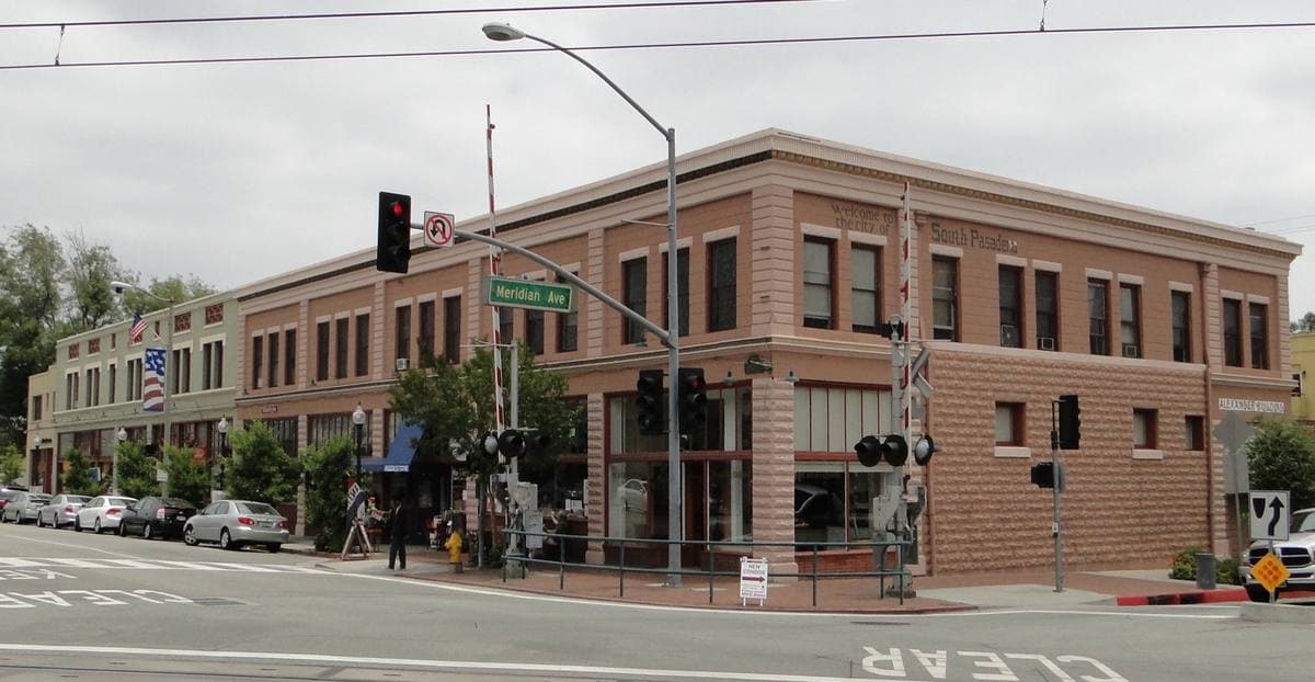 Two-storey red-brick commercial buildings on a street corner with traffic lights