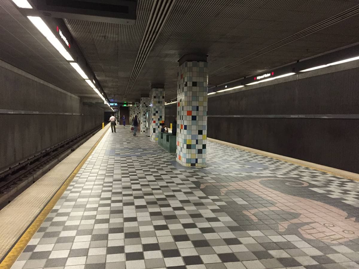 A long underground platform with a chequered floor and tiled columns