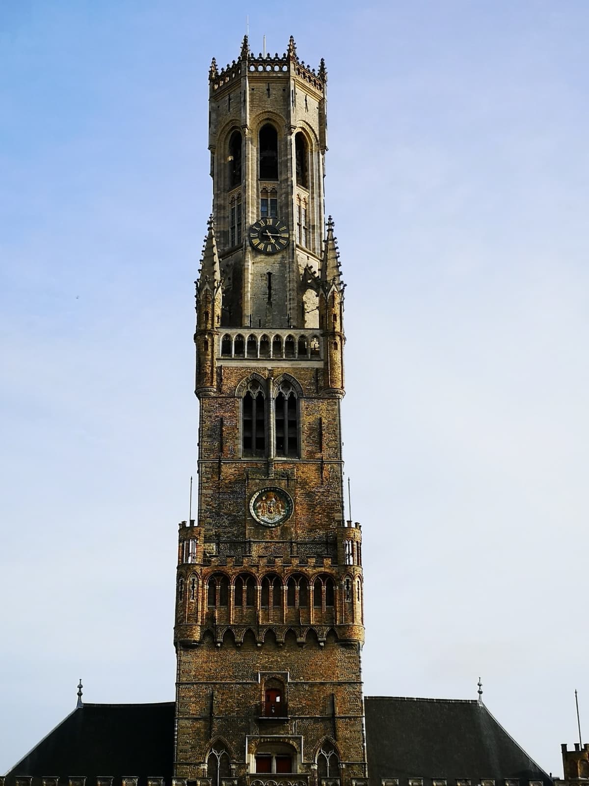 The tall brick Belfry tower of Bruges against a blue sky